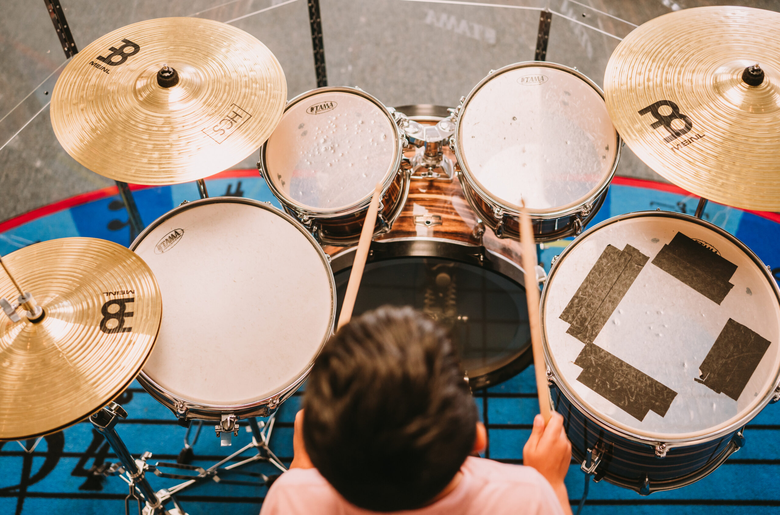 A boy sitting a a drum set play8ing the drums.